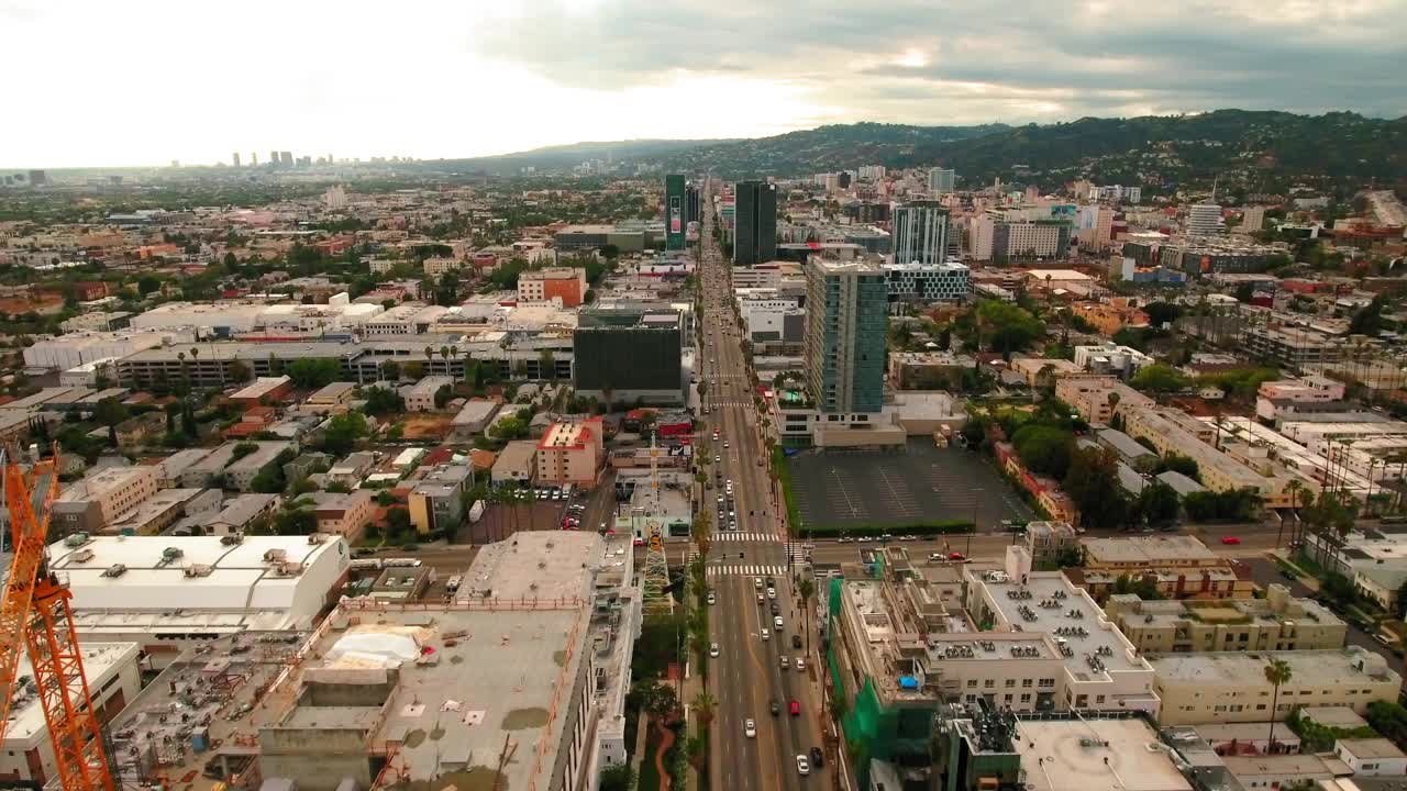 空中向前拍摄的车辆在道路上的建筑物在城市附近的山脉对天空-洛杉矶，加利福尼亚视频素材