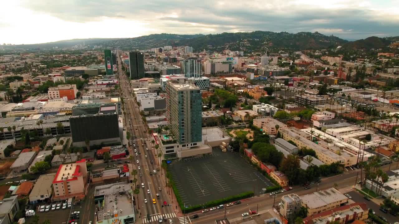 航拍拍摄的车辆在道路上的建筑物在城市附近的山脉对天空-洛杉矶，加利福尼亚视频素材