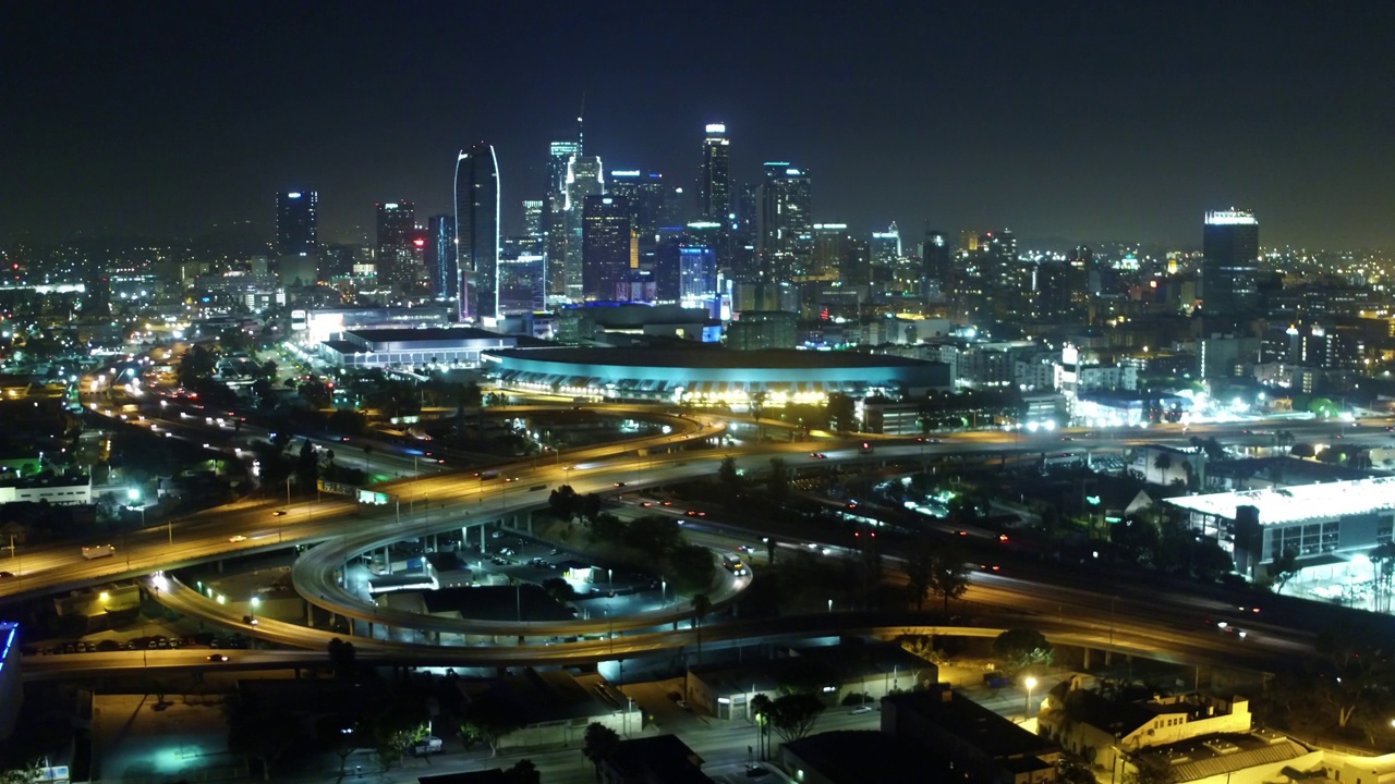 空中向前拍摄的车辆在城市摩天大楼附近的街道上对着天空在夜晚-洛杉矶，加利福尼亚视频素材