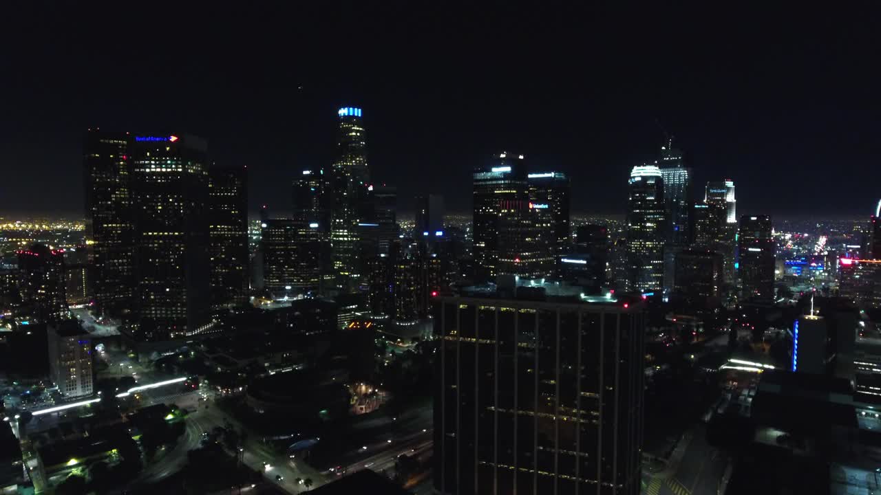 夜景中，城市中灯火通明的建筑物在天空的映衬下航拍向前——洛杉矶，加利福尼亚视频素材