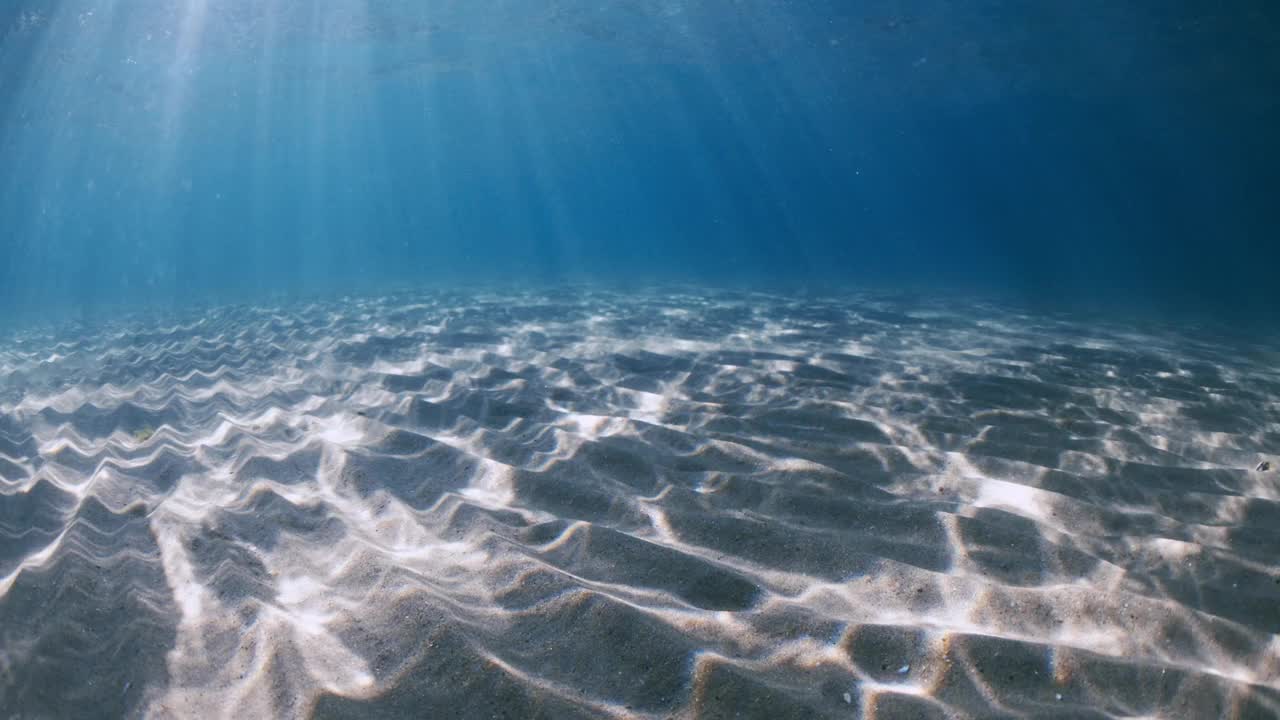 透明的蓝色海洋，海底有沙质，水下有阳光视频素材