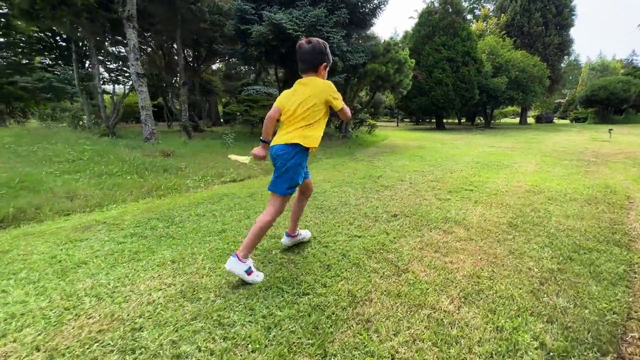 可爱的男孩笑着跑过草地。视频素材