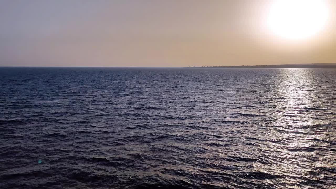 在大海上移动，天空和日落为背景，海岸在远处可见视频下载