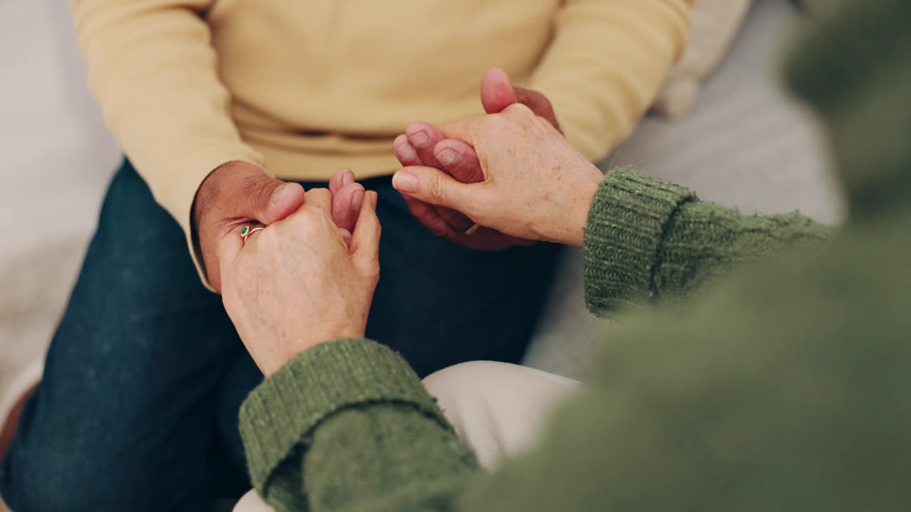 夫妻，爱和牵手的同情和支持或安全在家里的沙发上。男人和女人一起在客厅里的特写，在退休后寻求信任、同情和帮助或善意视频素材