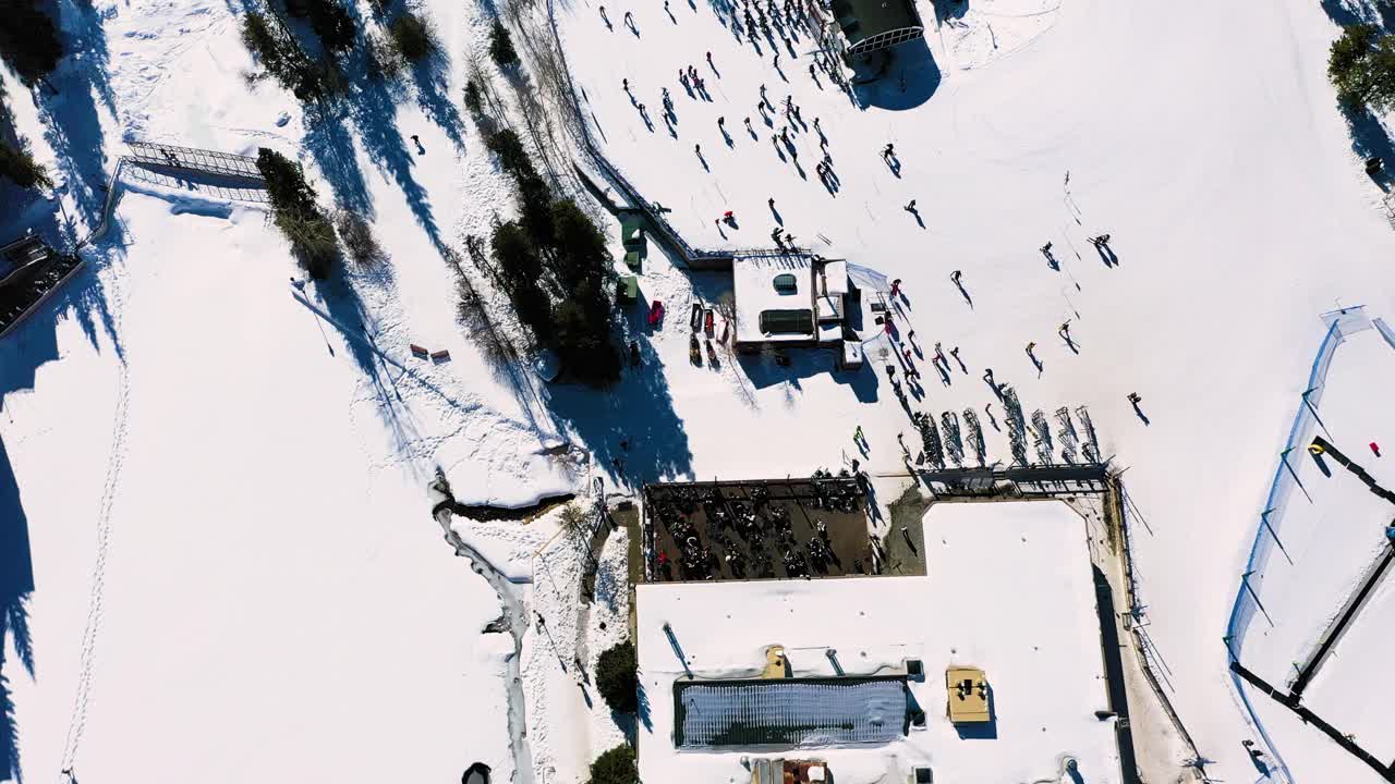 空中无人机拍摄的滑雪山坡上人们乘坐缆车的景象，揭示了高山和拥挤的小径视频素材