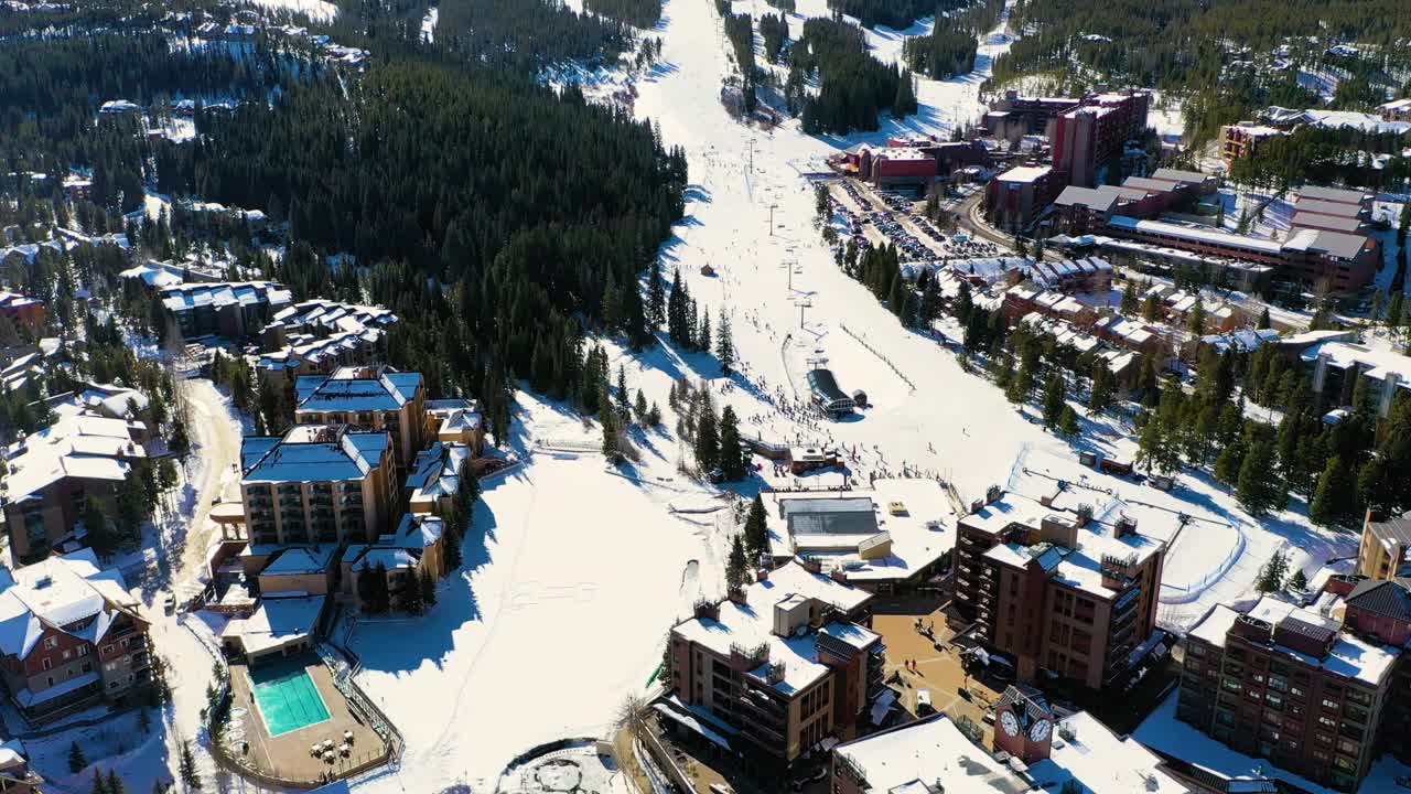 在布雷肯里奇，科罗拉多州滑雪胜地步道的空中无人机镜头。白雪覆盖的酒店和Cairlift视频素材