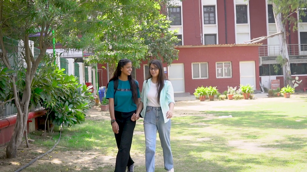 快乐的女性朋友一起走在大学校园里。视频素材