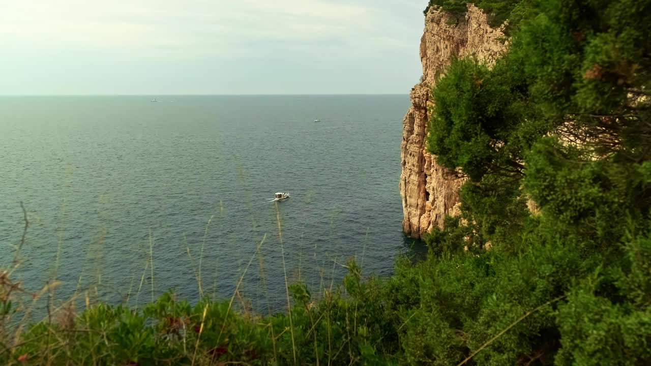 船在蓝色的大海上航行。高高的悬崖和高山。美丽的风景。波浪上的船。荒岛上视频素材