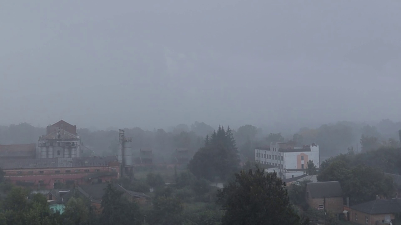 大雨、狂风和倾盆大雨倾泻在建筑物的背景上。城市的观点。多云的天空。城里下大雨。雨季视频下载