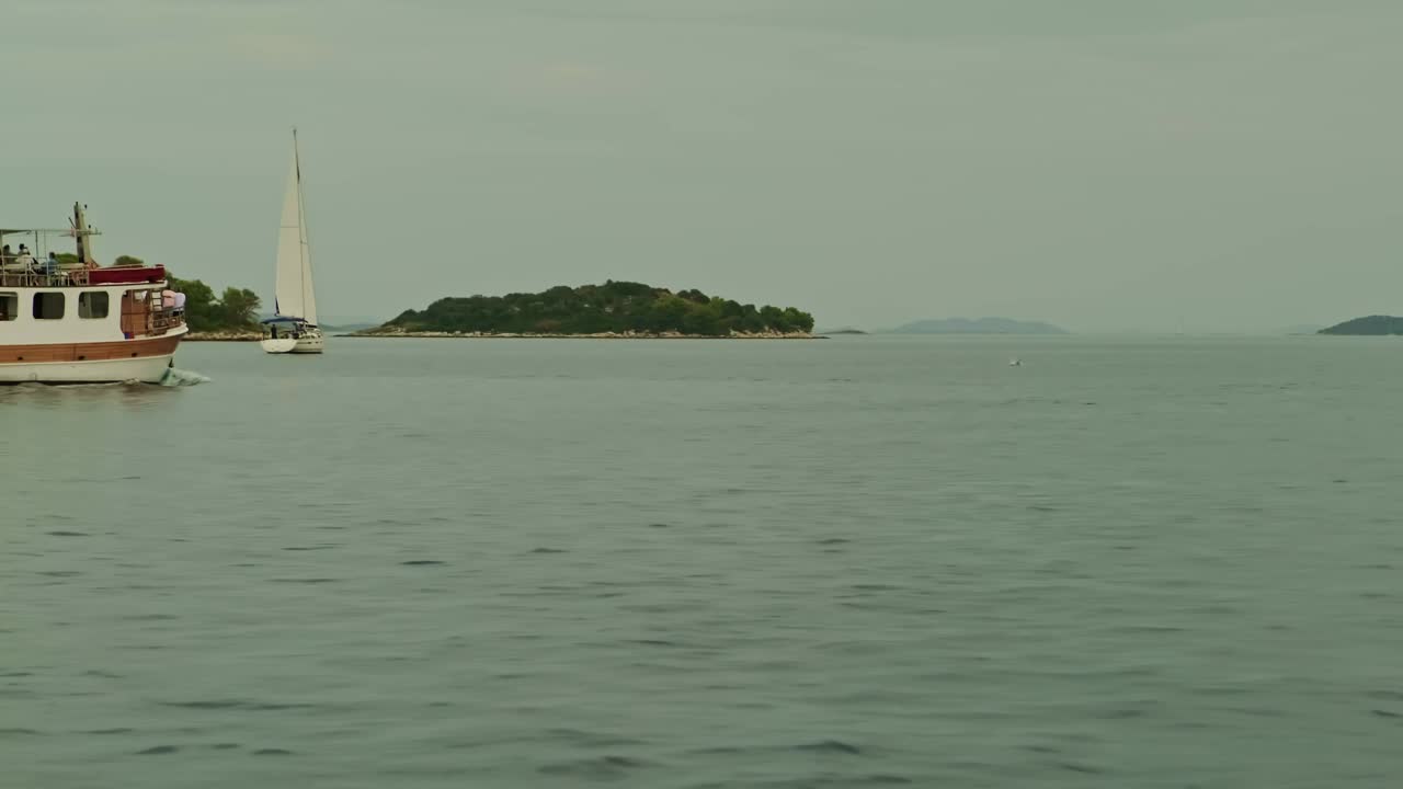 船在蓝色的大海上航行。高高的悬崖和高山。美丽的风景。波浪上的船。荒岛上视频下载