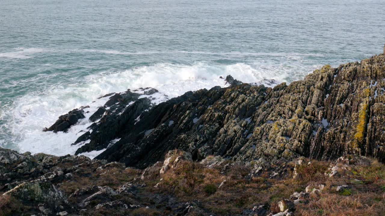 岩石嶙峋的海岸线，锯齿状的岩石在海浪的冲击下屹立不倒。深蓝色的大海，白色的泡沫从波浪。缩小视频素材