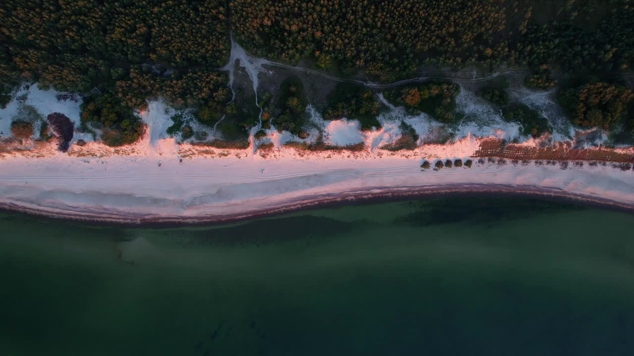 日落时白色沙滩上的海岸鸟瞰图。视频素材