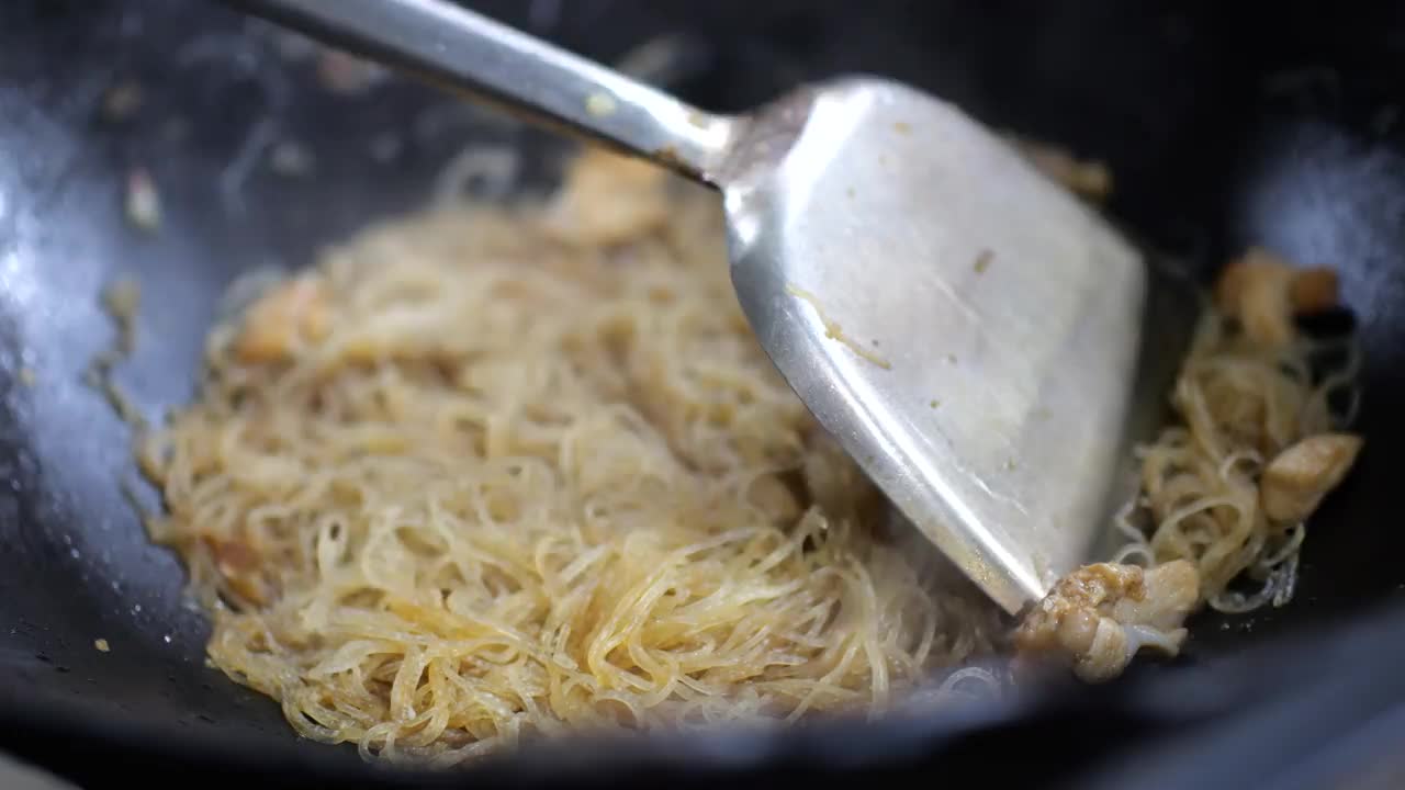 街边小吃店正在准备炒饭，也就是米粉。炒锅上炒米粉。视频素材