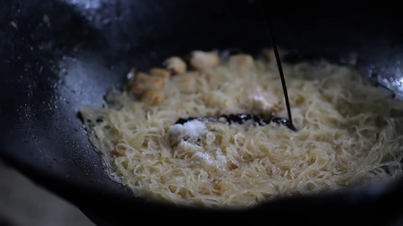 街边小吃店正在准备炒饭，也就是米粉。炒锅上炒米粉。视频素材