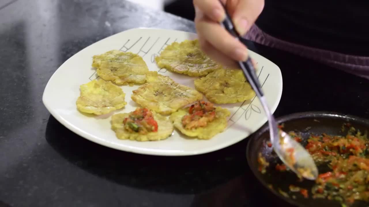 一个女人摆好盘子，把炖菜倒在压扁的大蕉上。典型的炖通心粉视频素材