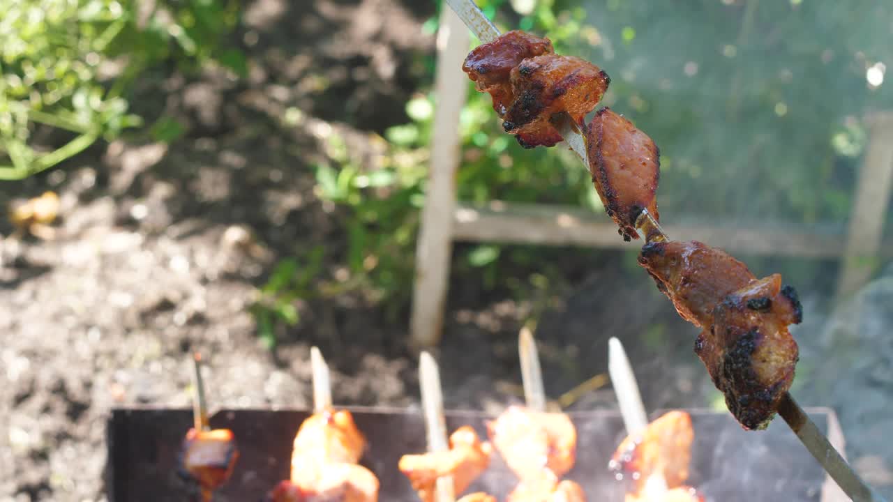 特写红肉串在金属棒上烧在煤上。在背景中，焦外，夏天的烧烤正在火上烤着视频素材