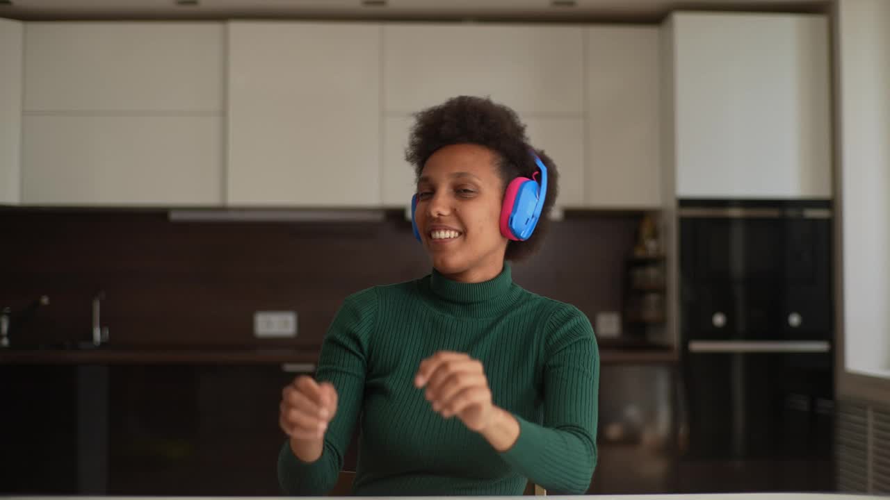 肖像的快乐无忧无虑的非洲裔年轻女子戴着无线耳机听着最喜欢的音乐乐队的声音跳舞视频素材