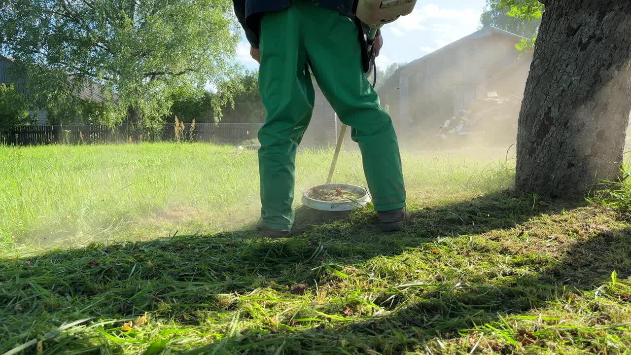 园丁修剪杂草。一个人在院子里用剪绳机割草。视频素材