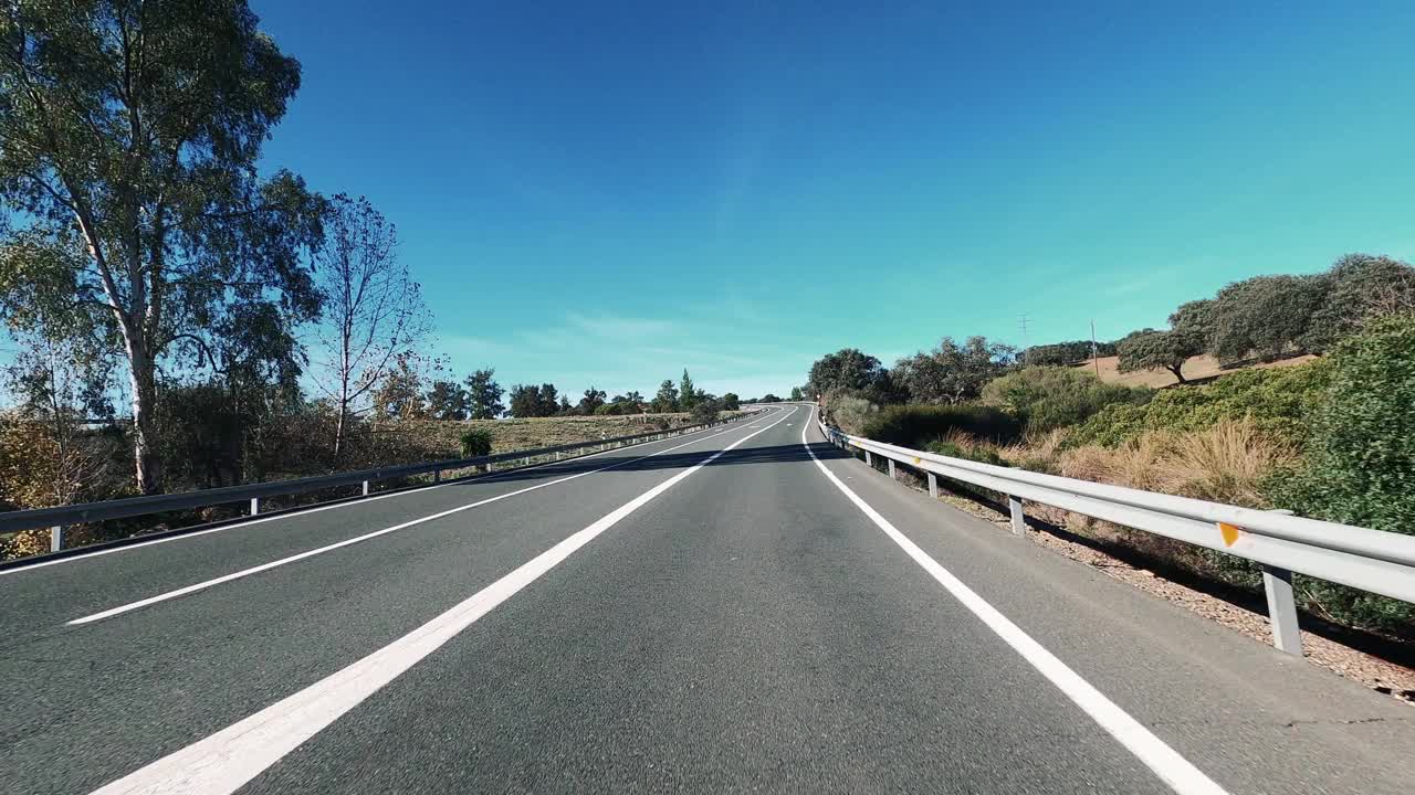 在蓝天和地平线的背景下，在一条长长的柏油直路上开车。旅游和交通的概念。山区国家公园。开车到目的地。节日假期。视频素材