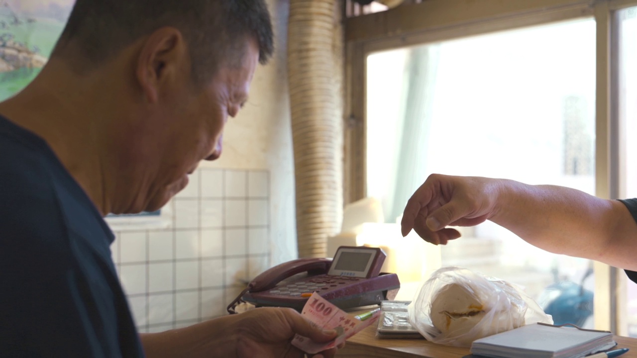 早餐店老板将馒头递给顾客，并收取现金视频素材