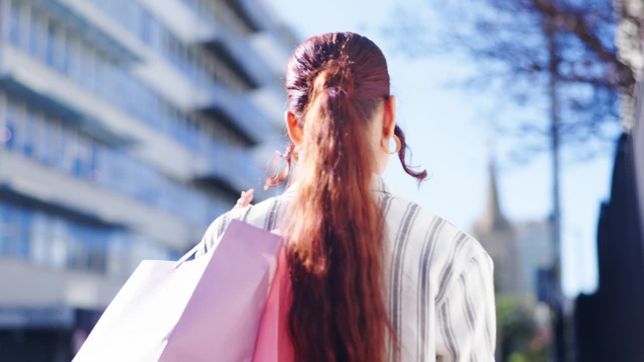 快乐的女人，步行和购物袋在城市打折，促销或户外购买。都市女性或购物者幸福、满足或时尚微笑的后视图视频素材