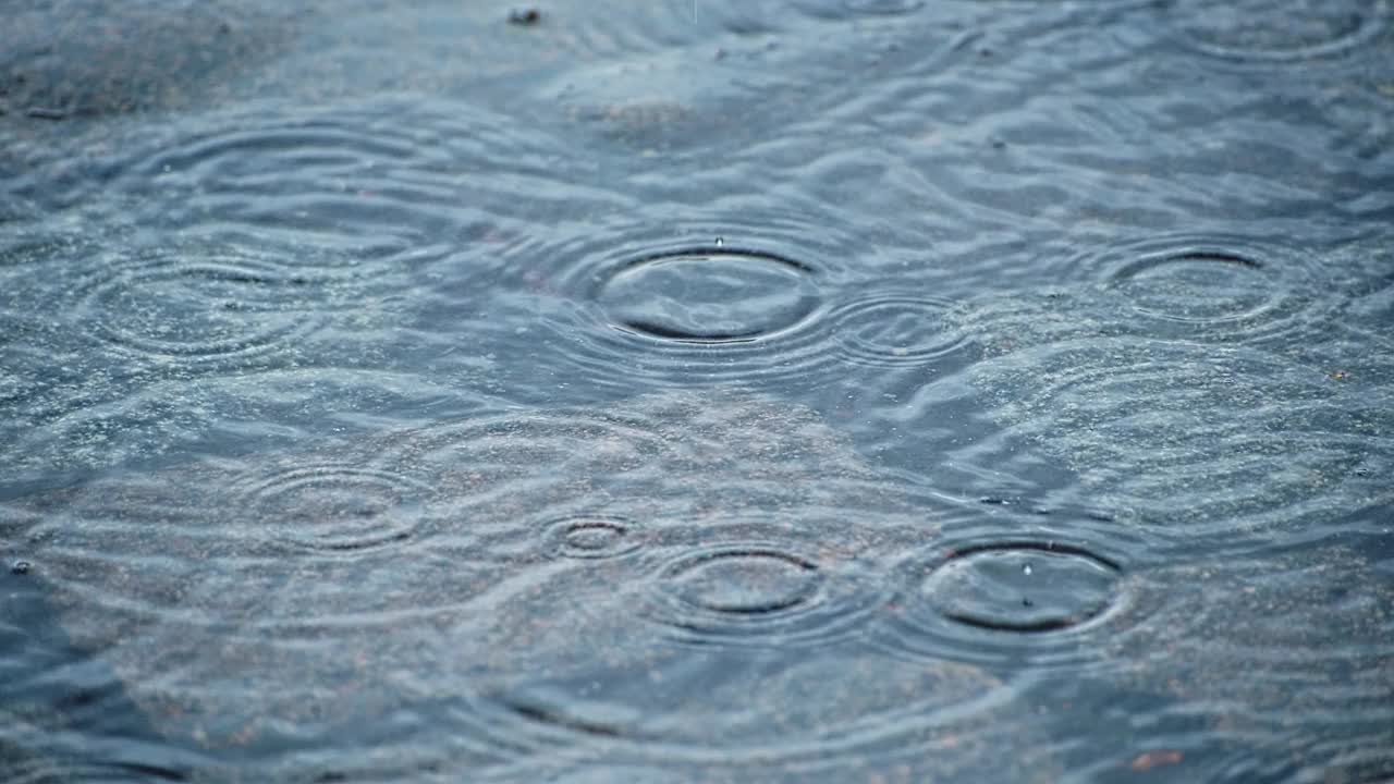 下雨时雨滴落在铺路石上的水坑里。视频素材