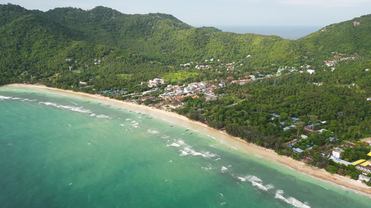 沙质海岸线的塞里海滩与海岸村庄和郁郁葱葱的山在涛岛，泰国。——空中视频素材