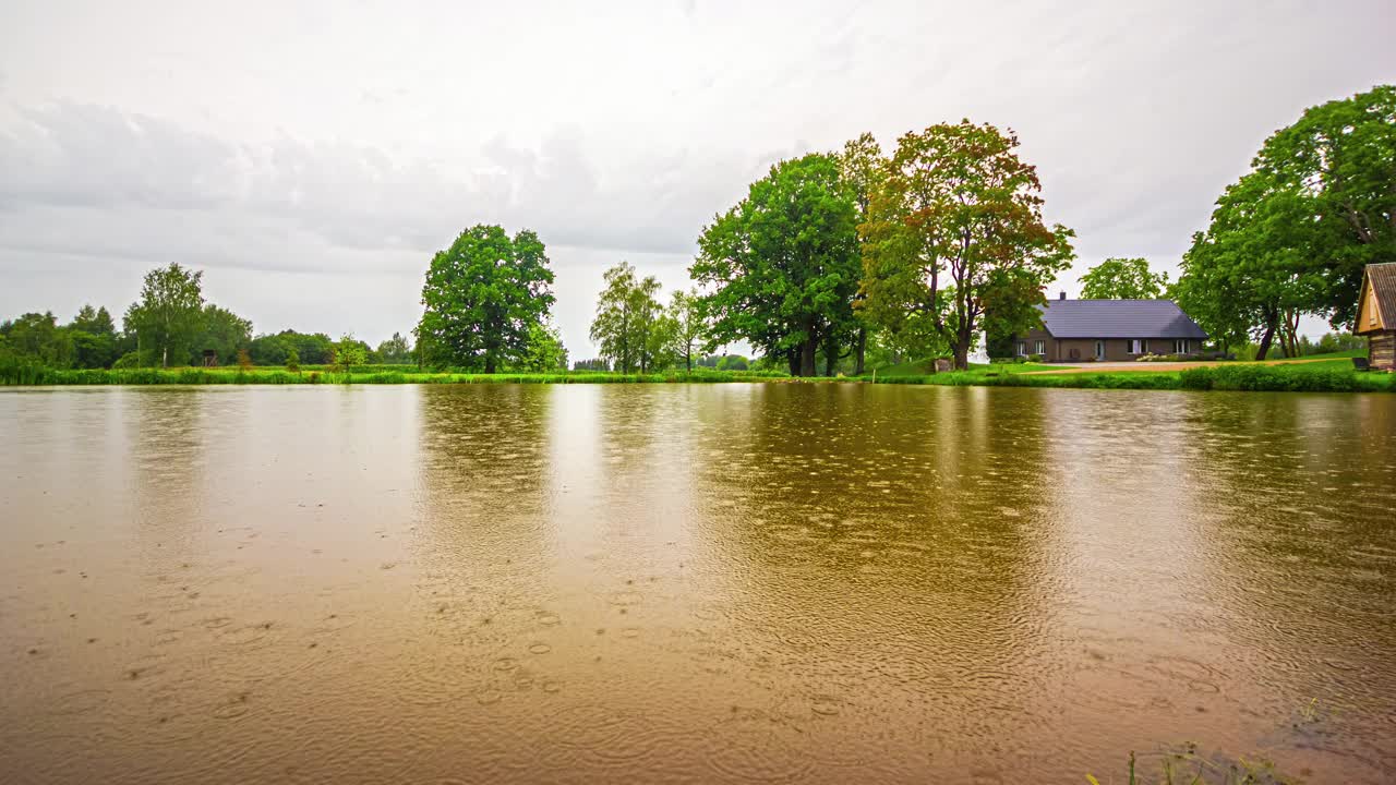 在雨水反射的湖面上的时间流逝。舒适的小屋沿着湖堤照亮了黄昏的来临。视频素材