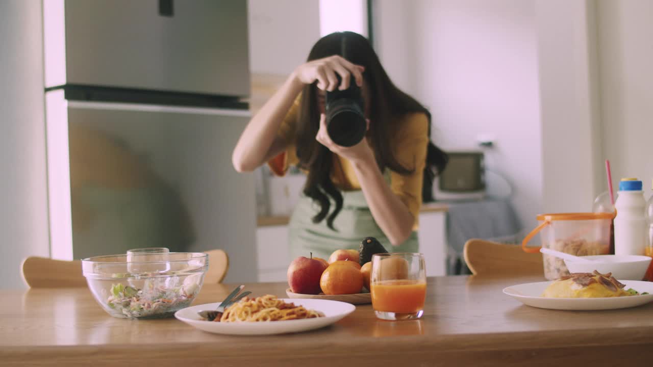 一位女性美食博主和网红用相机拍了一张照片，并在社交媒体上发表评论。视频素材