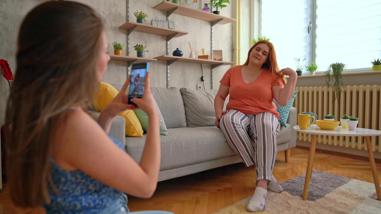 年轻女子在沙发上给她的朋友拍照视频素材