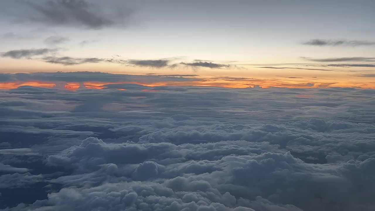 图为飞机在12000米高空飞过一层向西飞行的云层时拍摄的日落景象。一个独特的飞行员视角。视频素材