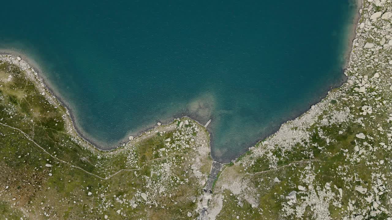 空中无人机的一个蓝色的高山湖泊与岩石海岸视图视频素材