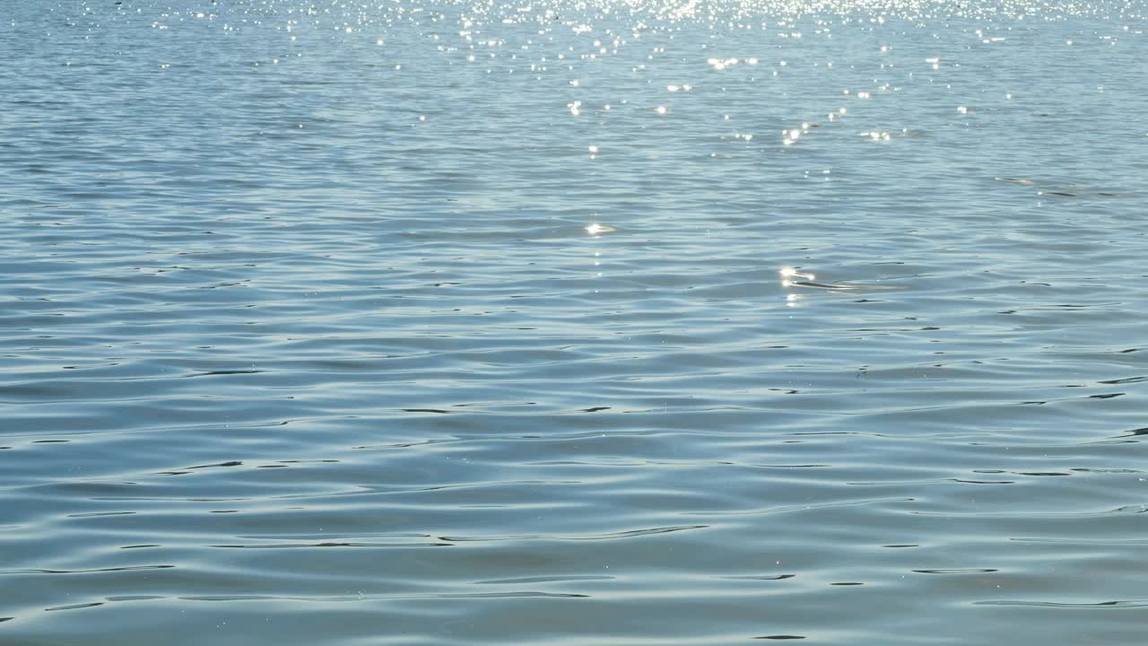 碧波荡漾的水面上闪闪发光的阳光，夏日的慢动作水波，旅游、休闲、度假或水质环境的自然场景背景视频素材