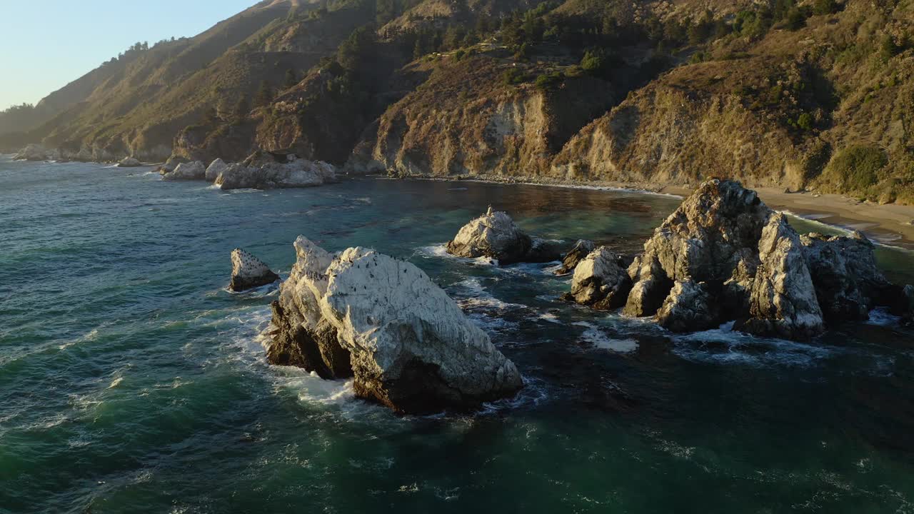 在金色的午后阳光下，沿着普费佛大苏尔州立公园地区崎岖的海岸线俯瞰岩石露头的航拍照片视频素材