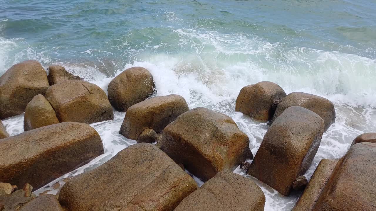 在越南宁顺省的Ca Na海滩上，海浪在岩石上飞溅和泡沫。海景优美，海水湛蓝。视频素材