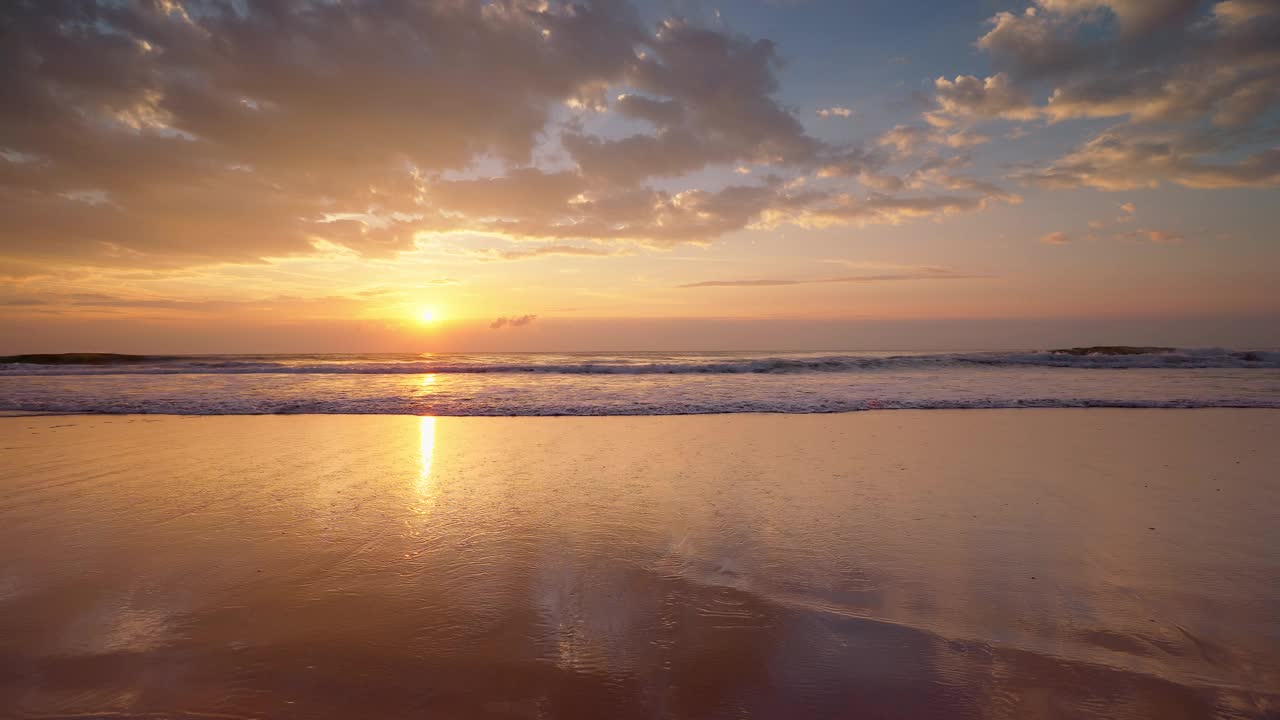 夏日的海洋沙滩日出，清晨的浪花溅在沙滩上，阳光反射在沙滩上视频素材