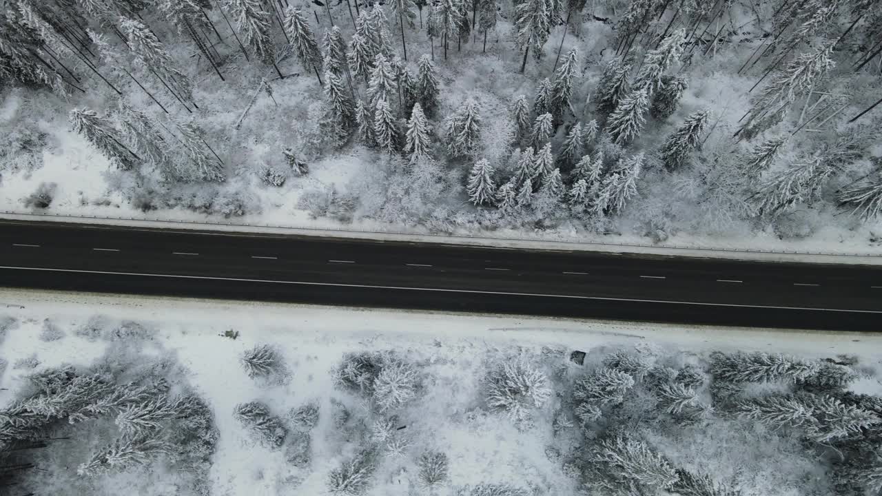 在芬兰的雪林中，汽车正行驶在被雪覆盖的道路上视频素材