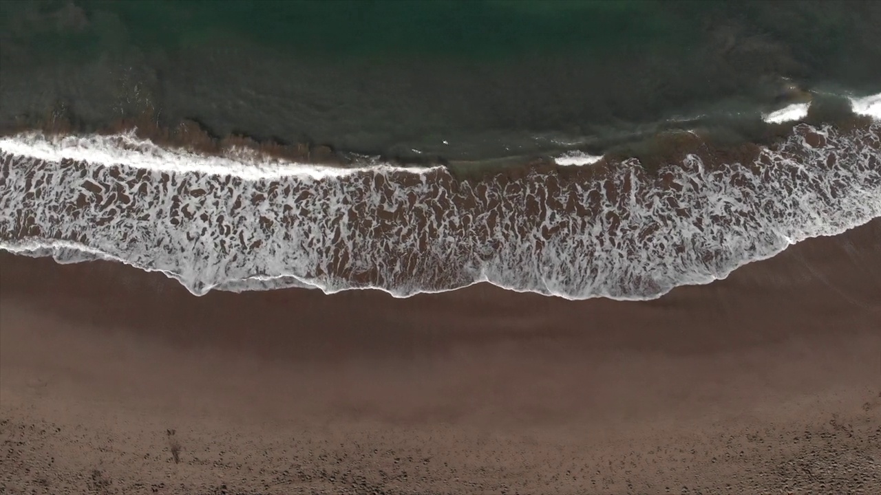 无人机沿着海洋沙滩野生海滩与海浪溅起白色泡沫。海洋的能量。鸟瞰4k视频。旅行旅游热视频素材