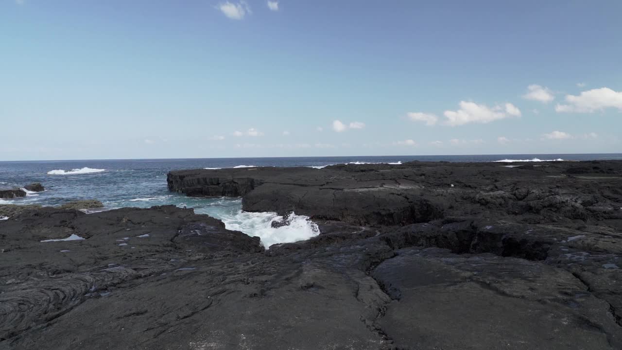 在一个阳光明媚的日子里，深蓝色的太平洋海浪冲击着加拉帕戈斯群岛的黑色火山熔岩。视频素材