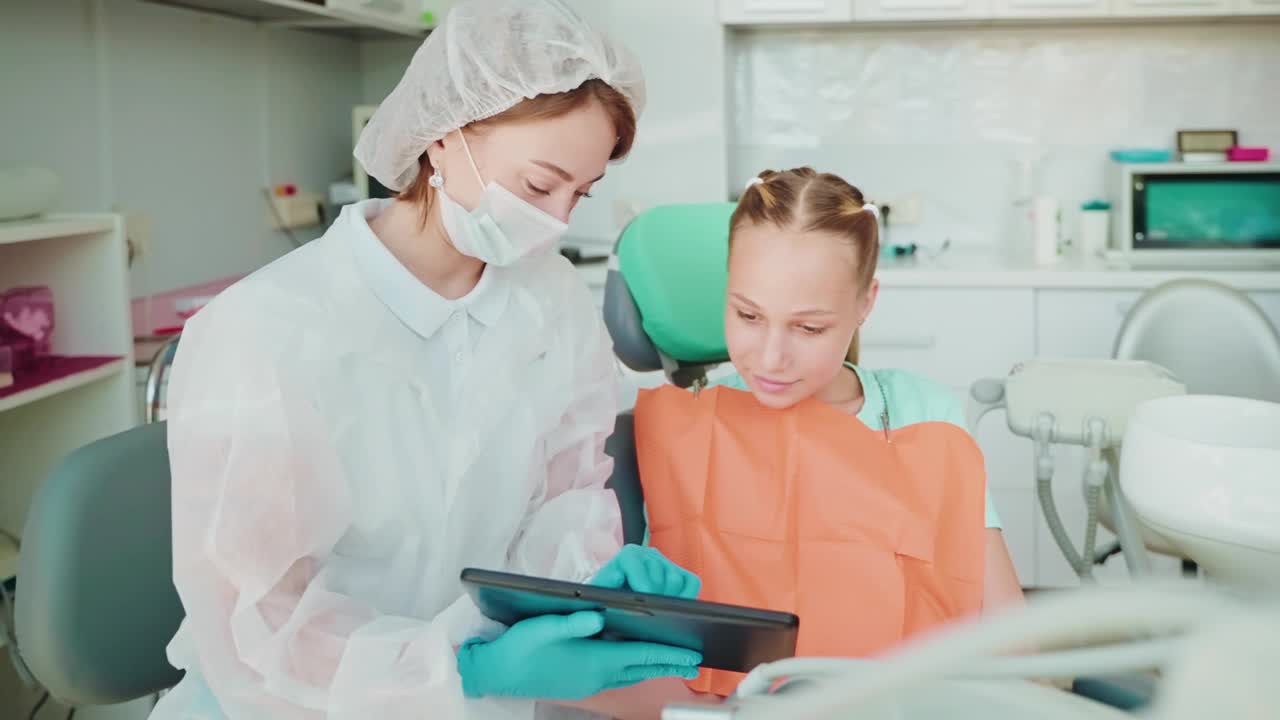 儿童在现代口腔诊所，女牙医和青少年女孩观看学习视频的教训视频素材