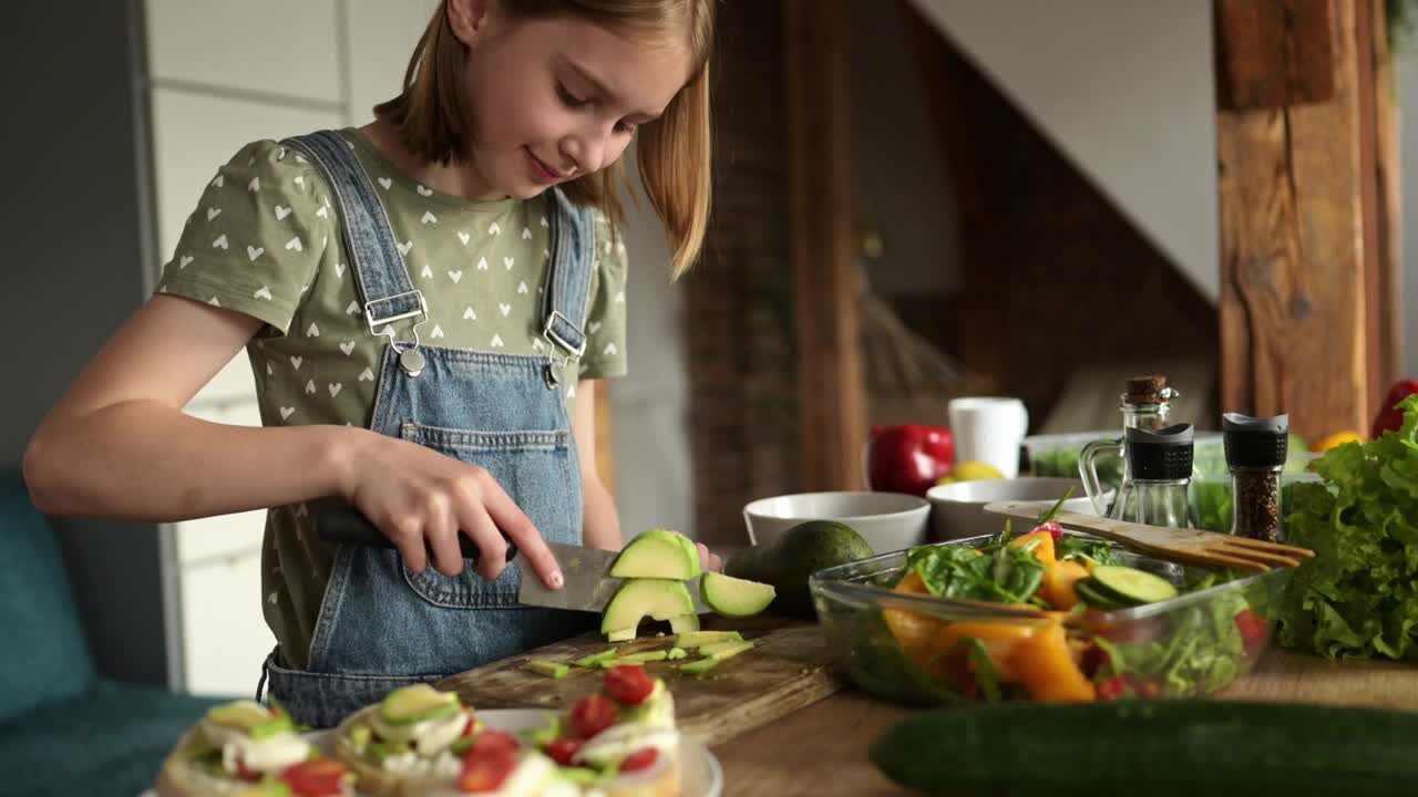 可爱的小女孩把牛油果切成健康的蔬菜沙拉视频素材