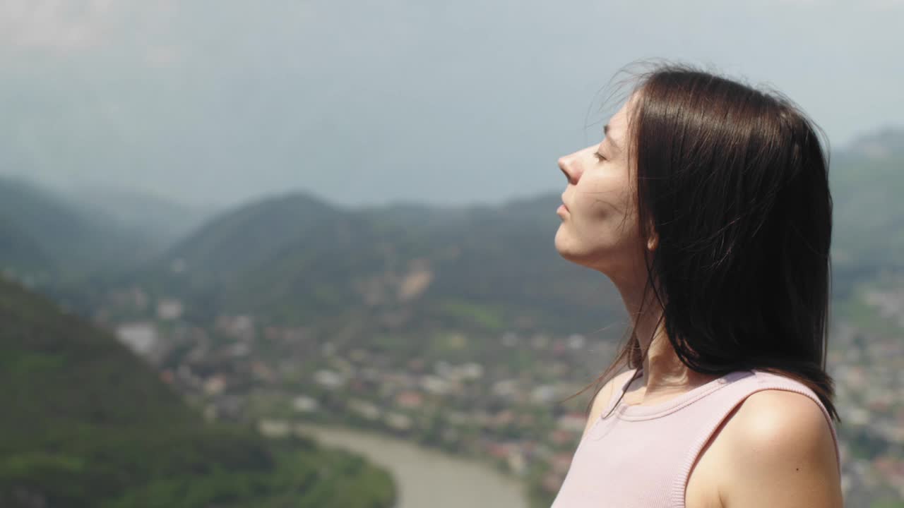 呼吸新鲜空气的年轻女子的侧影。年轻的黑发女性在城市背景下放松。旅游及旅游概念视频下载