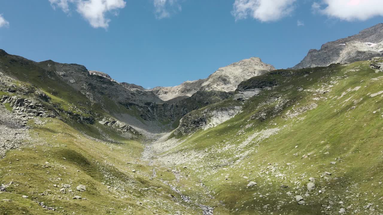 无人机鸟瞰图在一个山谷和周围的岩石山峰-意大利阿尔卑斯山视频素材