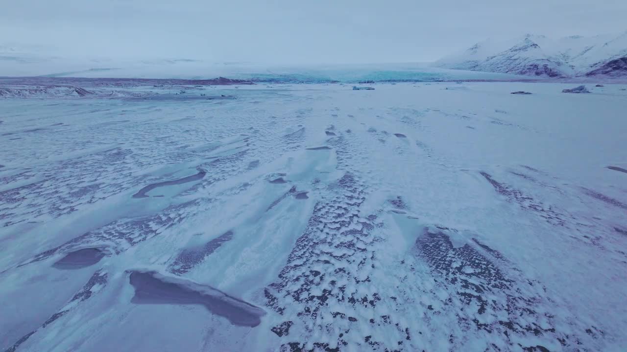 航拍全景俯瞰冰冻的Jokulsarlón湖地区，冰山覆盖在雪，在冰岛，黄昏视频素材