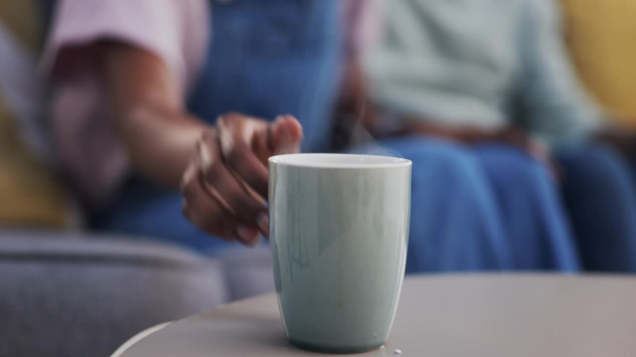 咖啡，聊天，一对幸福的黑人夫妇一起坐在他们家客厅的沙发上。茶，爱情或微笑，茶与一个男人和女人聊天，在他们的房子里喝饮料视频素材