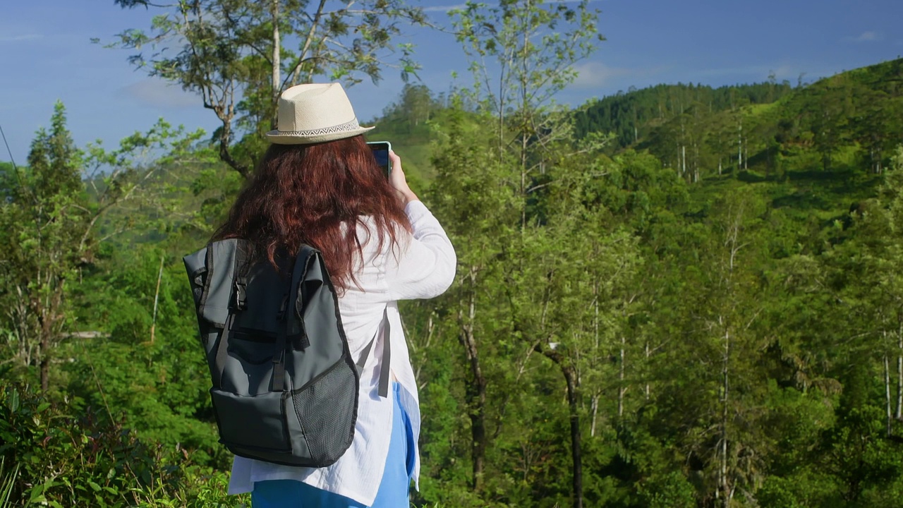 在阳光明媚的日子里，徒步旅行者拍摄森林美景的后视图视频素材