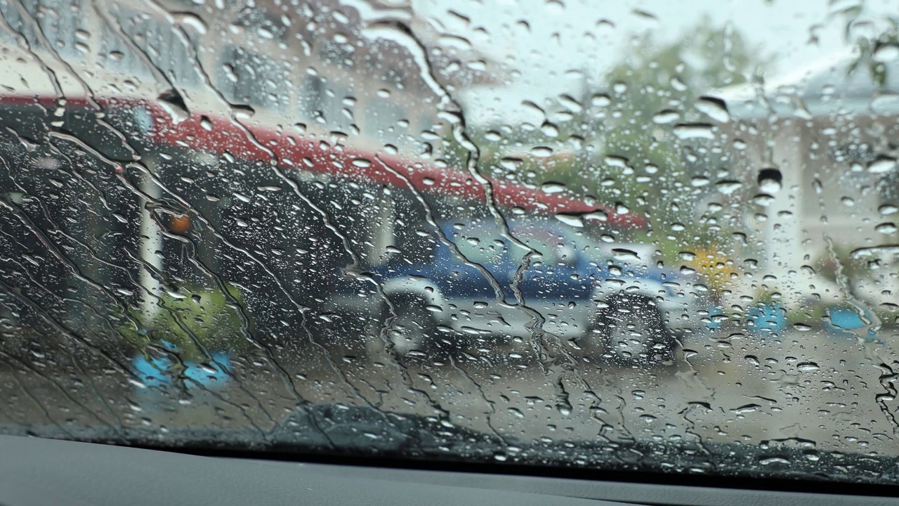 从一辆满是雨点的汽车的前窗往里看。视频素材