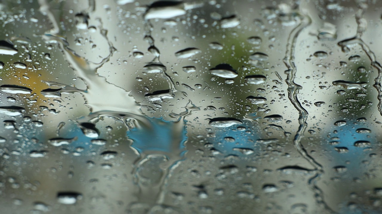 从车内透过雨点密布的汽车挡风玻璃的特写镜头。视频素材