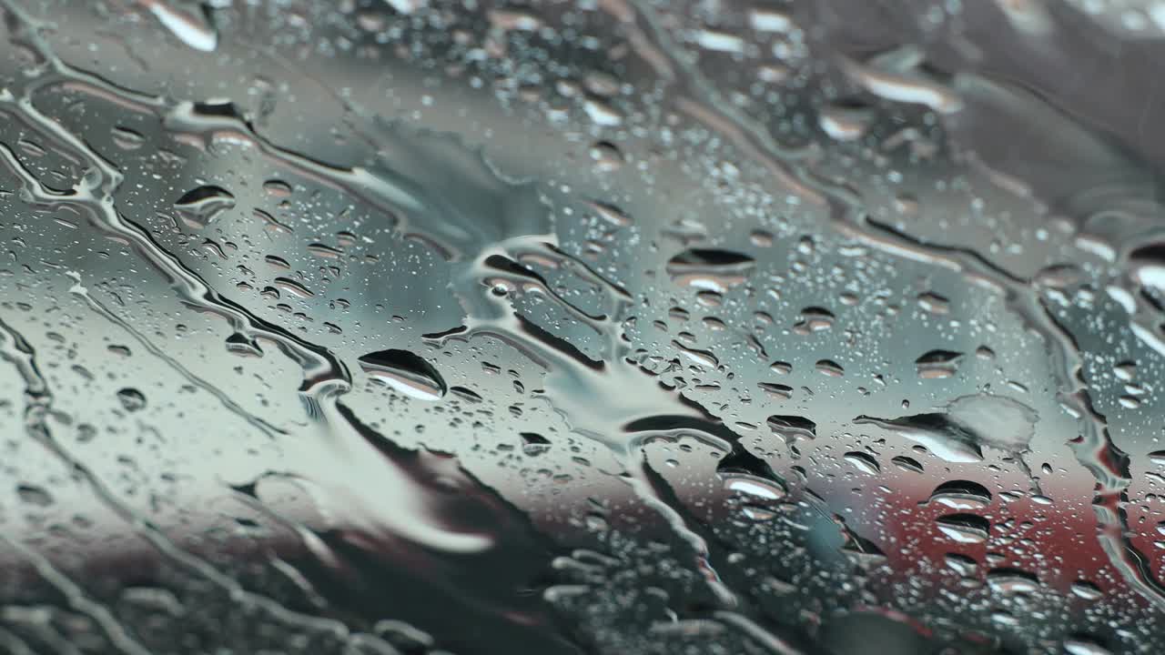透过一辆满是雨点和风的汽车的挡风玻璃看到的景象。视频素材