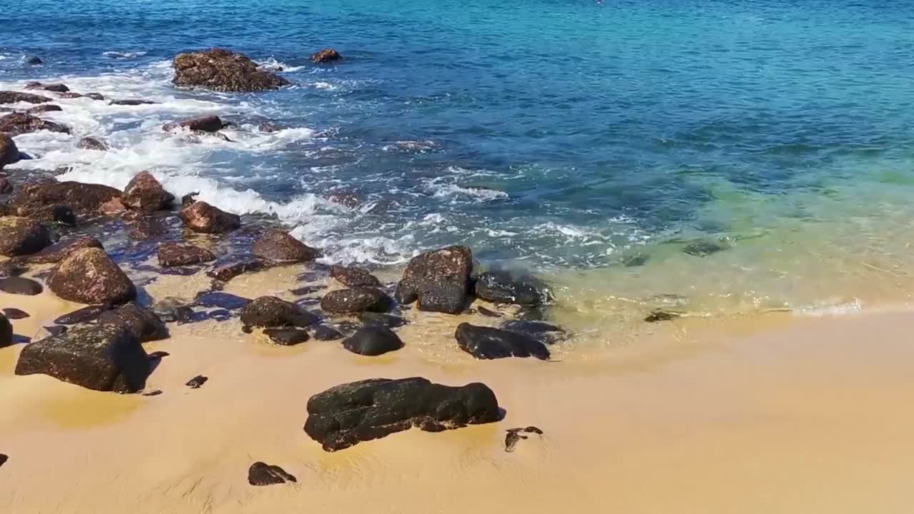 海滩沙滩蓝色绿松石水波浪岩石全景埃斯孔迪多港。视频素材